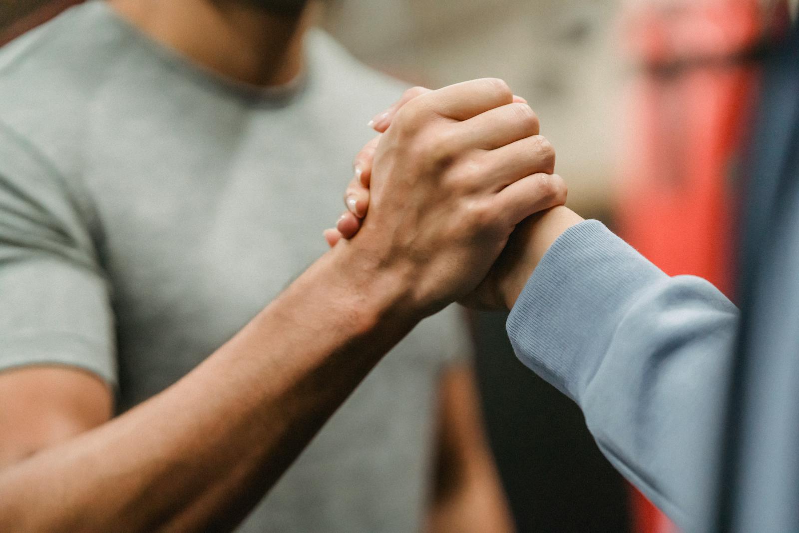 Photo by Julia Larson Close-up of a handshake between two individuals in a gym, symbolizing support and teamwork.